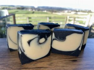 Image of 5 Lemon and Black Pepper soaps with a farm field in the background