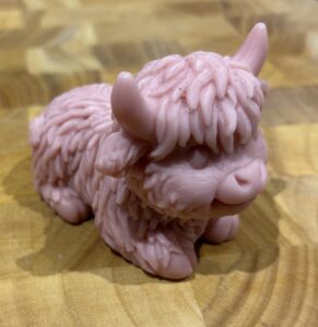 Image of a red/brown cow made of soap, on a wooden board