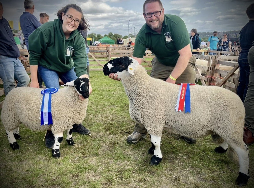 Two happy people exhibiting sheep and winning championship rosettes